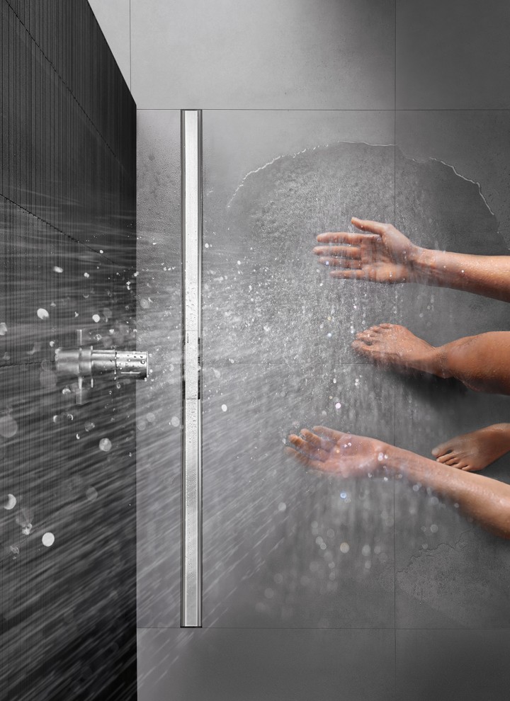 Человек принимает душ в душевой с ровным полом, оснащенной на уровне пола, оснащенной дренажным каналом Geberit CleanLine.