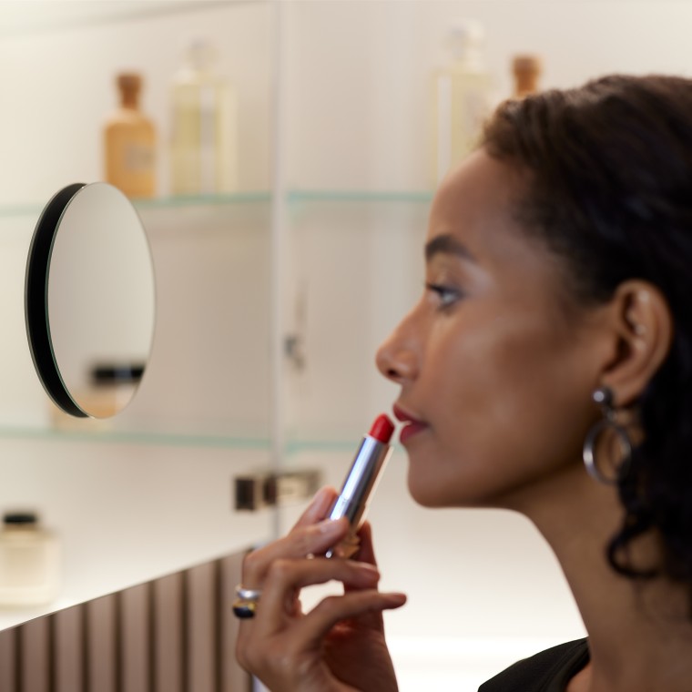 Женщина наносит макияж перед зеркалом