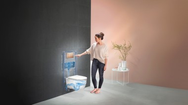 Девушка нажимает на смыв системы Geberit (© Geberit)