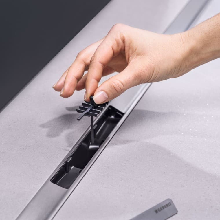 Рука помещает вставку-гребень в сифон Рука помещает вставку-гребень в сифон