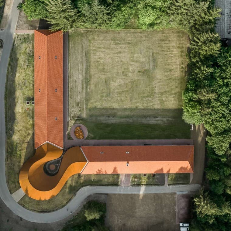 Вид сверху, круглое новое здание, соединяющее два исторических здания с черепичными крышами. (© R_Hjortshoj) Вид сверху, круглое новое здание, соединяющее два исторических здания с черепичными крышами. (© R_Hjortshoj)